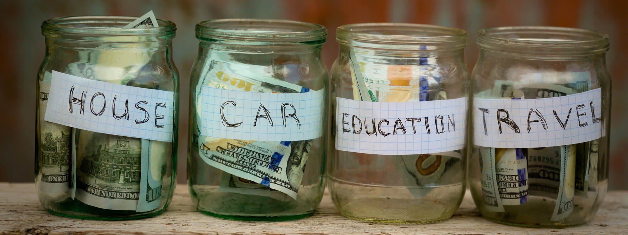 Banner of glass jars with dollars and text for house, car, education, and travel.