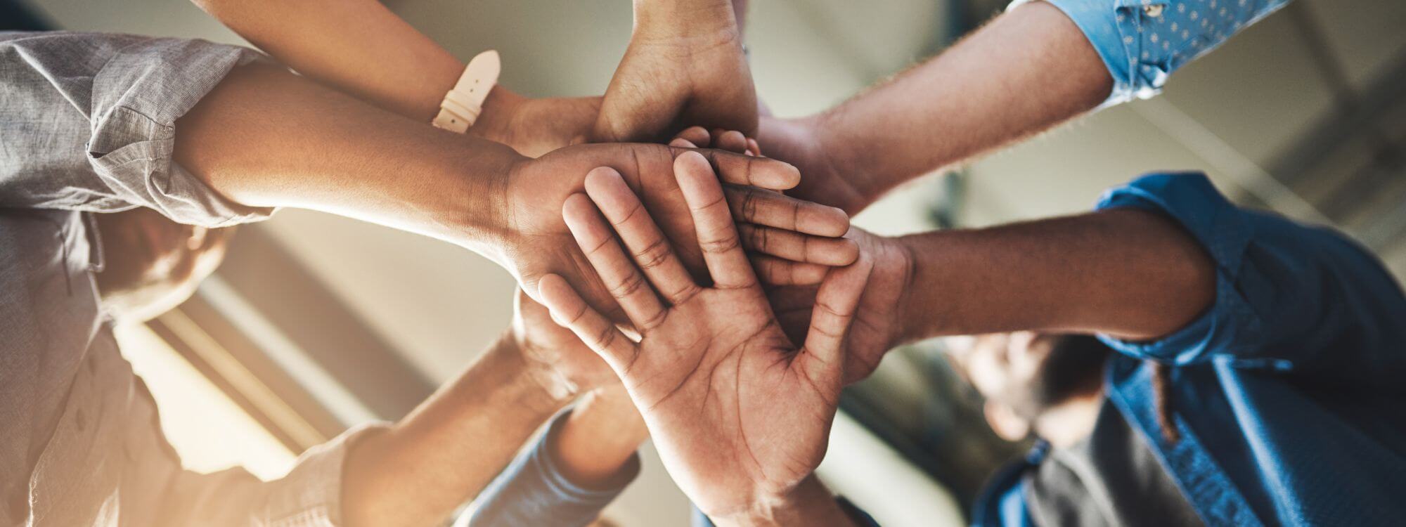 Banner for community showing people with stacked hands.