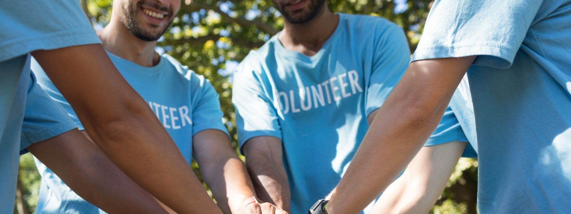 Banner image for KSW Cares showing volunteers stacking hands.