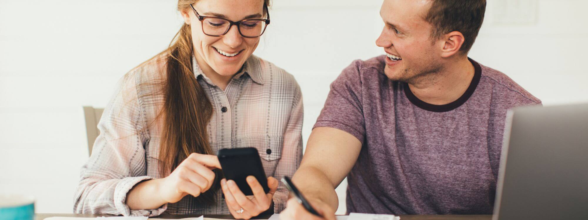 Banner image  of a woman and man using their phone and laptop.